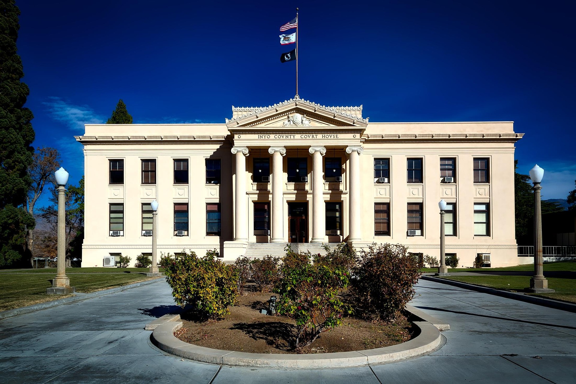 Historic county courthouse building with neoclassical architecture, columns, and flags displayed at the main entrance.