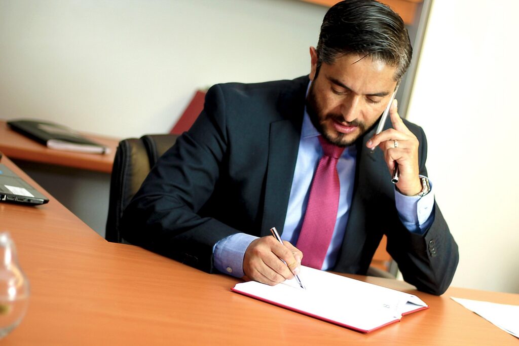 Attorney talking on the phone while reviewing legal documents and taking notes during case preparation.