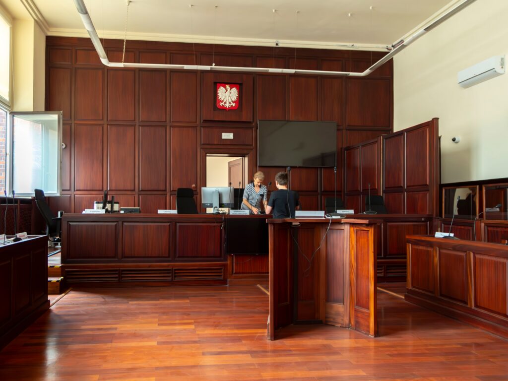 Interior view of an empty courtroom with the judge's bench, witness stand, and seating prepared for legal proceedings.